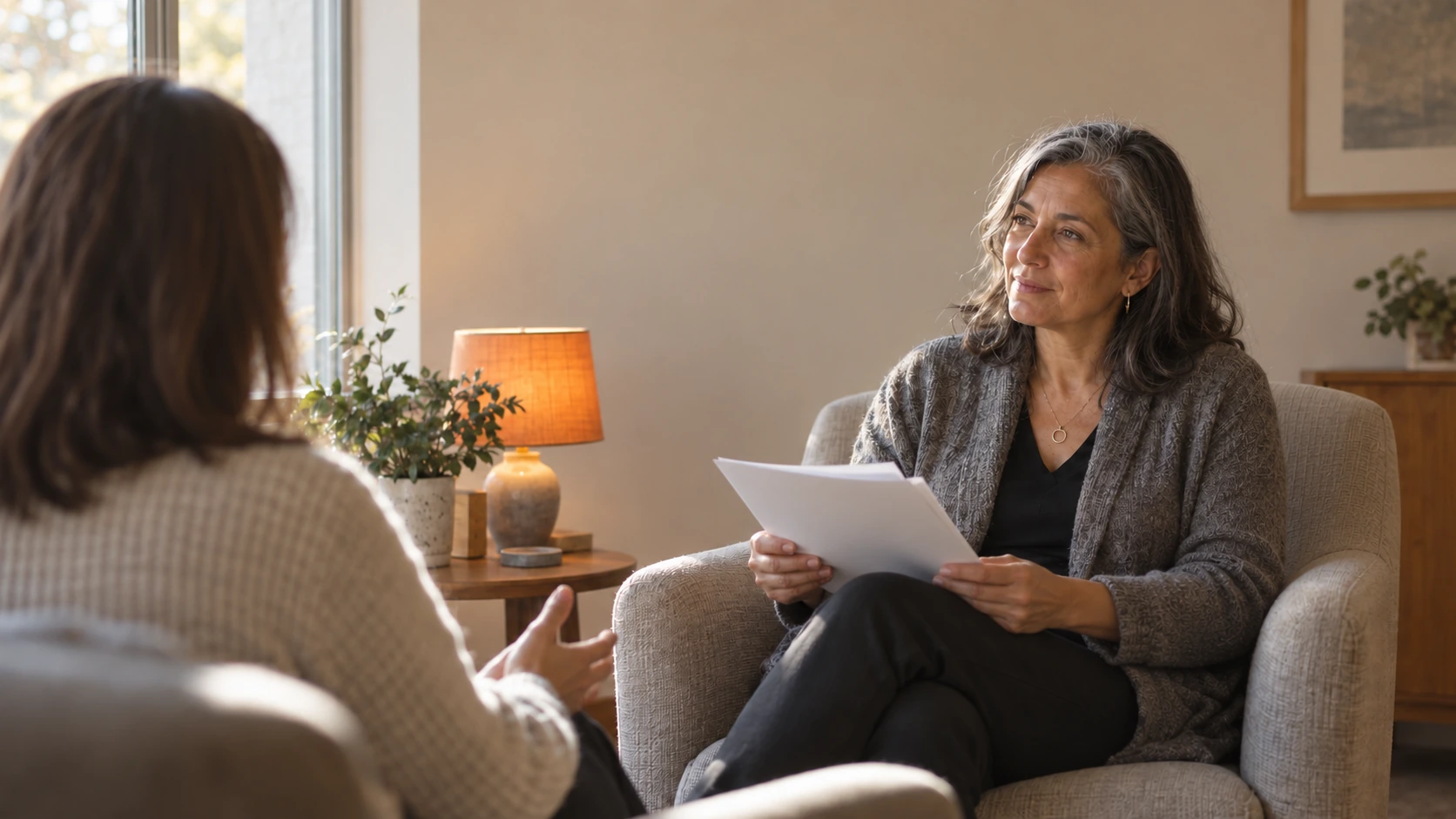 A naturopathic physician at a desk reviewing a printed partner agreement beside a laptop, warm morning light through the window.